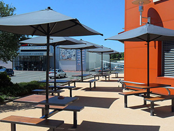 Tables et bancs extérieurs ligne Orpin avec parasols pour supermarché Systeme U