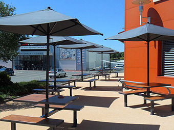 Tables et bancs extérieurs ligne Orpin avec parasols pour supermarché Systeme U